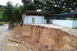 Lũ ống, lũ quét gây sạt lở nghiêm trọng, làm biến dạng bờ suối và cuốn trôi hoàn toàn một ngôi nhà tại bản Huổi Xá (xã Nhôn Mai, tỉnh Nghệ An); phần còn lại của ngôi nhà “treo” bên vách sạt lở. (Ảnh: Xuân Tiến/TTXVN)