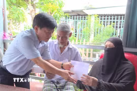 Ông Nguyễn Ngọc Huynh, Bí thư Đảng ủy, Chủ tịch Hội đồng Nhân dân xã Vĩnh Hậu (tỉnh An Giang), trao tiền hỗ trợ bước đầu cho các gia đình bị thiệt hại do hỏa hoạn tại ấp La Ma. (Ảnh: TTXVN phát)