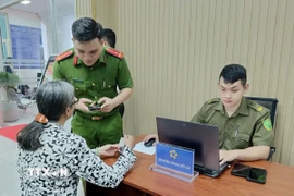 Công an hướng dẫn người dân tại bộ phận một cửa. (Ảnh: Linh Sơn/TTXVN)