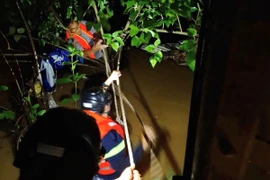 Lực lượng chức năng đu dây ra giữa dòng kênh để cứu người. (Ảnh: TTXVN phát)