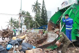 Xe thu gom rác và công nhân vệ sinh môi trường từ thành phố Hồ Chí Minh đến Khánh Hòa hỗ trợ thu gom rác trên bãi biển Nha Trang. (Ảnh: Phan Sáu/TTXVN)
