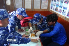 Cán bộ chiến sỹ tàu CSB 4035, Bộ Tư lệnh Vùng Cảnh sát biển 4 chăm sóc, hỗ trợ y tế cho ngư dân gặp nạn trên biển. (Ảnh: TTXVN phát)