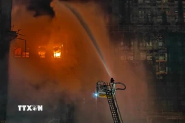 Lính cứu hỏa nỗ lực dập lửa tại hiện trường cháy tòa chung cư ở quận Tai Po, Hong Kong (Trung Quốc) ngày 26/11. (Ảnh: THX/TTXVN)