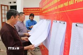 Người dân xem danh sách cử tri được niêm yết. (Ảnh: Mạnh Minh/TTXVN)