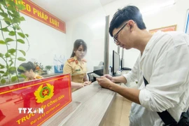 Cán bộ, chiến sỹ Công an phường Cửa Nam, thành phố Hà Nội tiếp nhận và hướng dẫn người dân đến làm thủ tục đăng ký xe môtô. (Ảnh: Phạm Kiên/TTXVN)