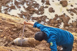 Lực lượng dân quân tự vệ thị trấn Phước Cát kiểm tra vật thể nghi là bom do người dân phát hiện khi đào hồ chứa nước. (Ảnh: TTXVN phát)