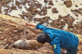 Lực lượng dân quân tự vệ thị trấn Phước Cát kiểm tra vật thể nghi là bom do người dân phát hiện khi đào hồ chứa nước. (Ảnh: TTXVN phát)