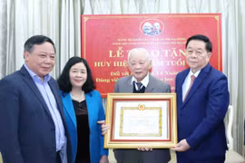 Trưởng Ban Tuyên giáo Trung ương Nguyễn Trọng Nghĩa trao Huy hiệu 65 năm tuổi Đảng cho ông Lê Xuân Tùng. (Ảnh: Phương Hoa/TTXVN)
