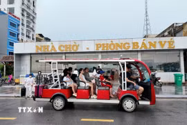 Các du khách đi xe điện ra cảng tàu để lên tàu trở về đất liền. (Ảnh: Thu Báu/TTXVN phát)