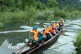 Thầy cô giáo Trường Tiểu học và Trung học cơ sở Thượng Hóa (xã Kim Phú, Quảng Trị) di chuyển bằng thuyền qua đoạn ngập ở Hung Trâu để đến trường. (Ảnh: Tá Chuyên/TTXVN)