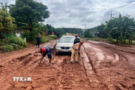 Lực lượng công an, dân quân địa phương khẩn trương dọn dẹp, khắc phục tình trạng sạt lở tràn ra Quốc lộ 14C gây ách tắc và nguy hiểm cho người tham gia giao thông. (Ảnh: TTXVN phát)