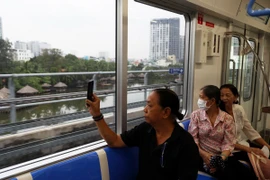 Người dân lưu lại hình ảnh đô thị bên ngoài khi trải nghiệm tuyến metro số 1. (Ảnh: Huyền Trinh/TTXVN)