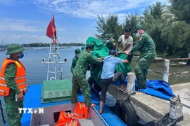 Cán bộ chiến sỹ Đồn biên phòng Tam Thanh chuyển thi thể nạn nhân vào đất liền. (Ảnh: TTXVN phát)