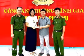 Công an phường Tĩnh Gia và chị Lê Thị Huyền trao trả lại tài sản cho người bỏ quên. (Ảnh: TTXVN phát)