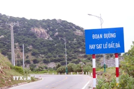 Lực lượng chức năng gắn biển cảnh báo tuyến đường hay xảy ra sạt lở để người và phương tiện thận trọng khi qua tuyến đường ven biển. (Ảnh: Công Thử/TTXVN)