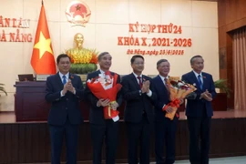 Chủ tịch Ủy ban Nhân dân thành phố Đà Nẵng Lê Trung Chinh (thứ hai từ trái sang) và Chủ tịch Ủy ban Mặt trận Tổ quốc Việt Nam thành phố Đà Nẵng Lê Văn Trung (thứ từ từ trái sang) nhận hoa chúc mừng của Thường trực Hội đồng Nhân dân thành phố Đà Nẵng. (Ảnh: Quốc Dũng/TTXVN)
