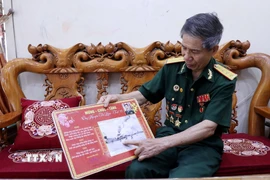 Cựu chiến binh Nguyễn Thế Liêm giới thiệu về bức ảnh 'Truy kích địch trong sân bay Tân Sơn Nhất.' (Ảnh: Quang Cường/TTXVN)