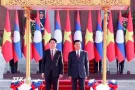 Chủ tịch nước Lương Cường và Tổng Bí thư, Chủ tịch nước Lào Thongloun Sisoulith trên bục danh dự, nghe quân nhạc cử Quốc thiều hai nước. (Ảnh: Lâm Khánh/TTXVN)