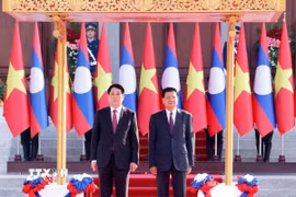 Chủ tịch nước Lương Cường và Tổng Bí thư, Chủ tịch nước Lào Thongloun Sisoulith trên bục danh dự, nghe quân nhạc cử Quốc thiều hai nước. (Ảnh: Lâm Khánh/TTXVN)