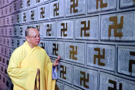 Thượng tọa Thích Thanh Cường giới thiệu bức tường đá khắc chữ 'Vạn' tại chùa Cương Xá được công nhận Kỷ lục châu Á. (Ảnh: Mạnh Tú/TTXVN)