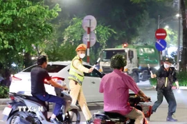 Cán bộ, chiến sỹ thuộc tổ công tác liên ngành Y6/141 dừng xe kiểm tra và xử lý 1 trường hợp vi phạm giao thông. (Ảnh: Phạm Kiên/TTXVN)