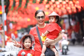 Nhiều người dân lưu lại khoảnh khắc với hình ảnh cờ Tổ quốc tại phố Hàng Mã, phường Hoàn Kiếm, Hà Nội. (Ảnh: Khánh Hòa/TTXVN)