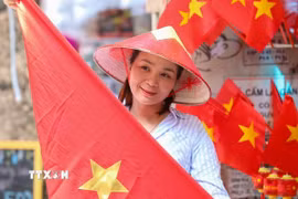 Người dân lưu lại khoảnh khắc với hình ảnh cờ Tổ quốc. (Ảnh: Khánh Hòa/TTXVN)