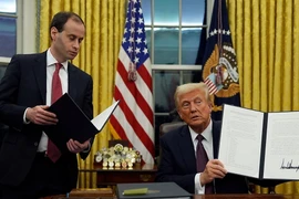 Tổng thống Mỹ Donald Trump (phải) ký sắc lệnh hành pháp ngay sau lễ nhậm chức, tại Nhà Trắng ở Washington DC., ngày 20/1/2025. (Ảnh: AP/TTXVN)