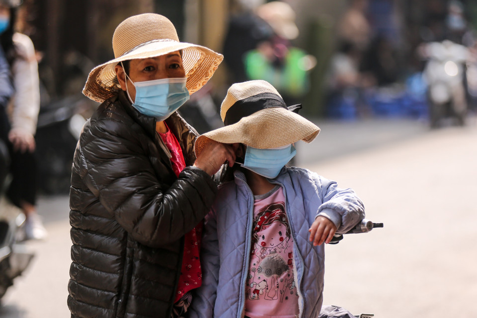 Một phụ huynh đang đeo khẩu trang cho con em mình trước khi ra ngoài. (Ảnh: Minh Sơn/Vietnam+)