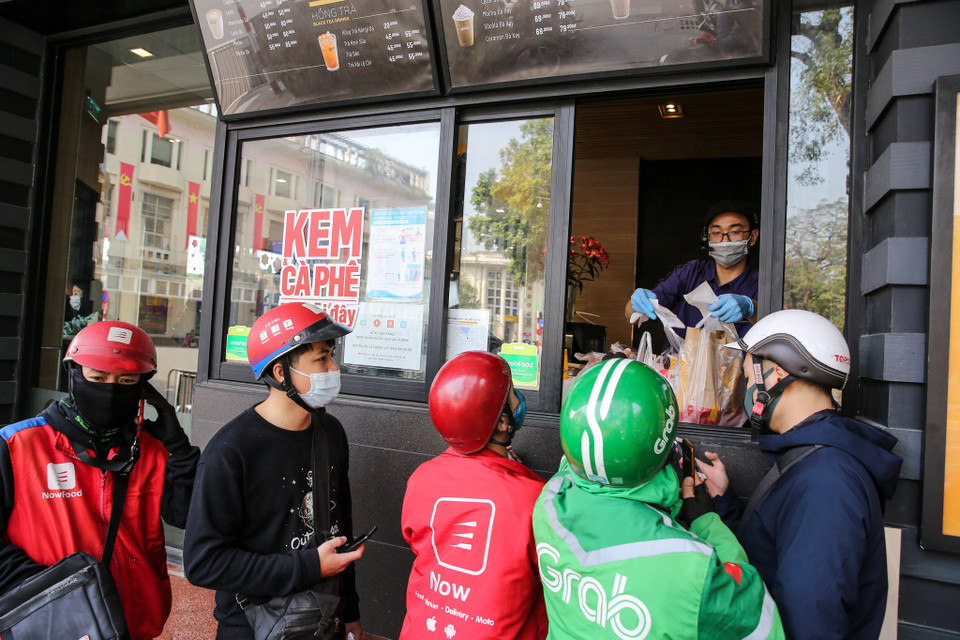 Một nhà hàng trên phố đi bộ Hồ Gươm đã yêu cầu các tài xế giao hàng phải đeo khẩu trang khi giao nhận đồ, đồng thời các nhân viên nơi đây cũng thực hiện các biện pháp bảo hộ an toàn. (Ảnh: Minh Sơn/Vietnam+)
