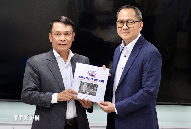 베트남 언론인 협회 상임부회장 응우옌 득 러이(왼쪽)가 베트남 통신사 80주년 기념 사진집을 CCJ 뿌이께 회장에게 전달하고 있다. (사진: 꽝 아인/VNA) ttxvn-bao-chi-truyen-thong-trong-ky-nguyen-so-8359375.jpg