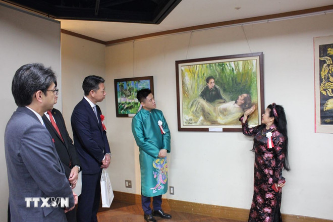 Female artist Van Duong Thanh introduces a painting about President Ho Chi Minh. (Photo: Pham Tuan/VNA) ttxvn-chu-tich-ho-chi-minh.jpg