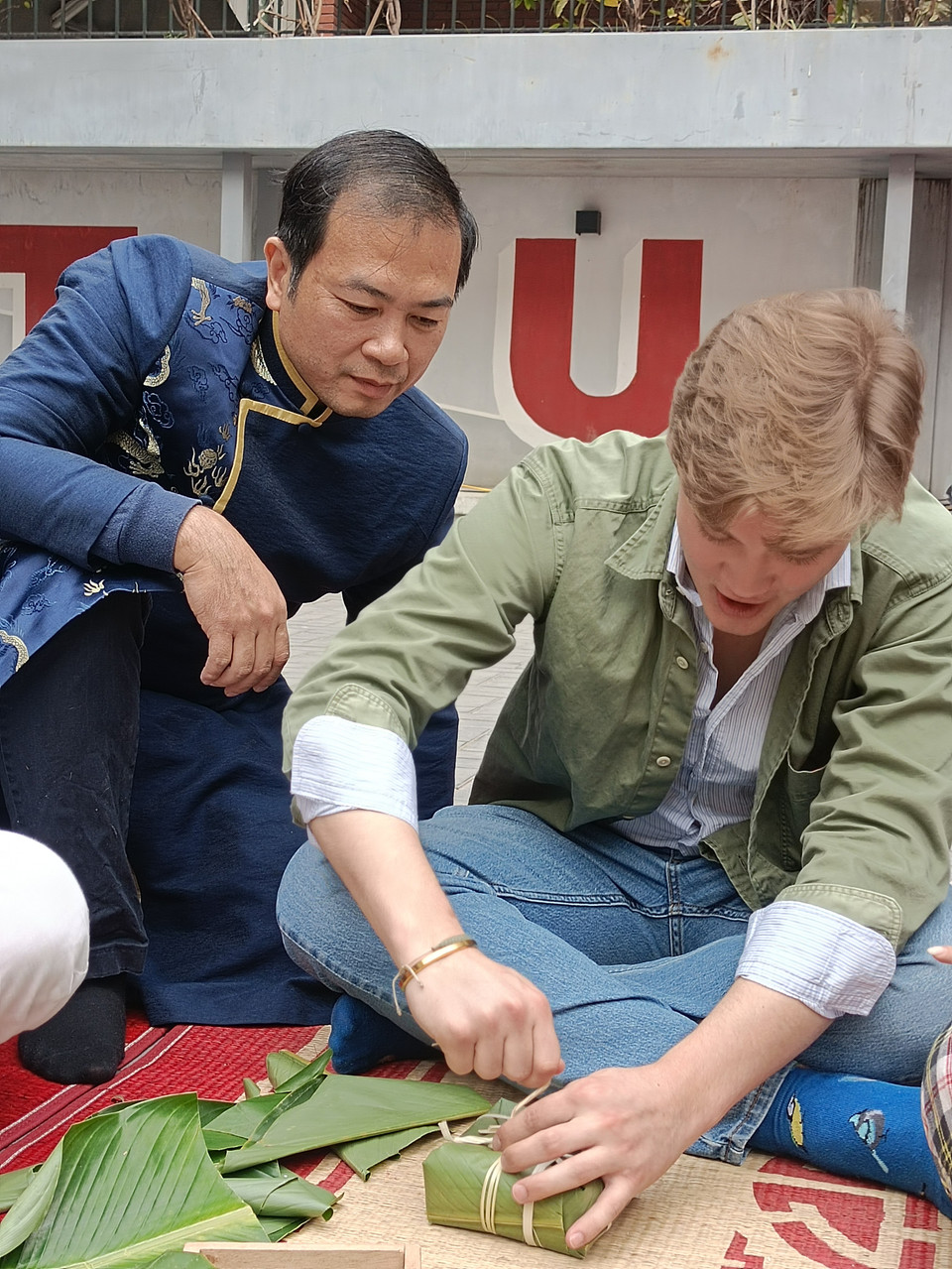 Gói bánh sao cho vuông vức và buộc lạt sao cho chặt là công đoạn được các sinh viên đánh giá khó khăn nhất. (Ảnh: PV/Vietnam+)