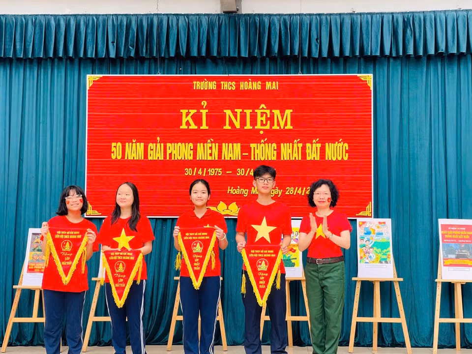 Nhân dịp này, nhà trường cũng phát động và tổng kết cuộc thi thiết kế poster cổ động tuyên truyền chào mừng kỷ niệm 50 năm ngày giải phóng miền Nam. Cô Hiệu trưởng Chu Thị Xuân Hường trao cờ cho các tác phẩm xuất sắc nhất. (Ảnh: PV/Vietnam+)