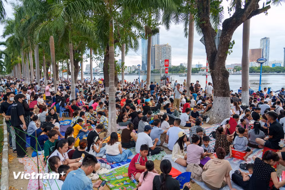Từ đầu giờ chiều 11/7, hàng vạn người dân và du khách đã trải thảm, ngồi kín vỉa hè dọc bờ sông Hàn để chờ đón đêm chung kết Lễ hội pháo hoa Đà Nẵng (DIFF) 2026. (Ảnh: Thanh Phong/Vietnam+)