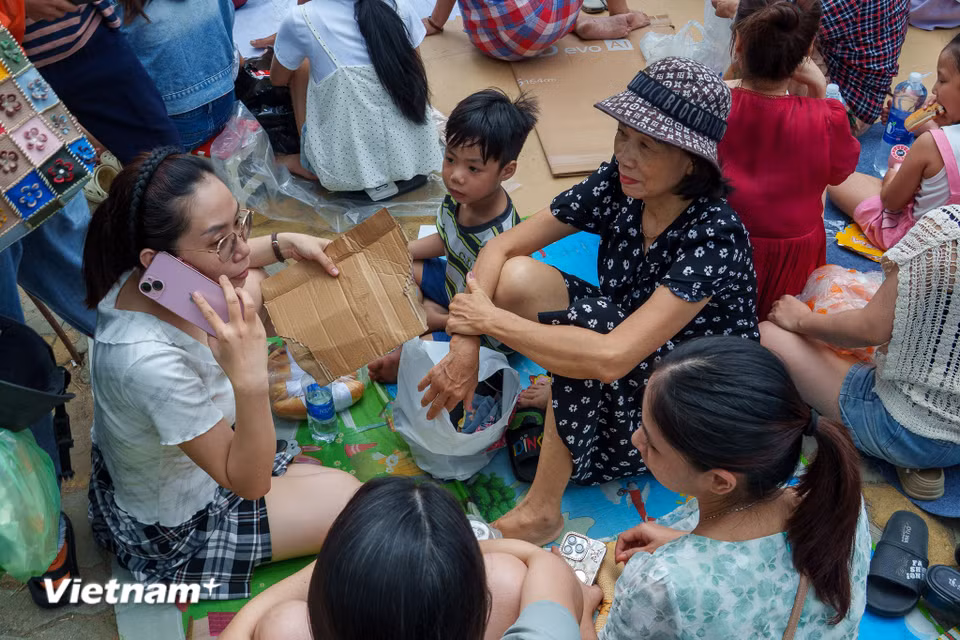Những tấm bìa carton được tận dụng lót chỗ ngồi và trở thành cái quạt tạm để xua tan không khí oi nóng. (Ảnh: Thanh Phong/Vietnam+)