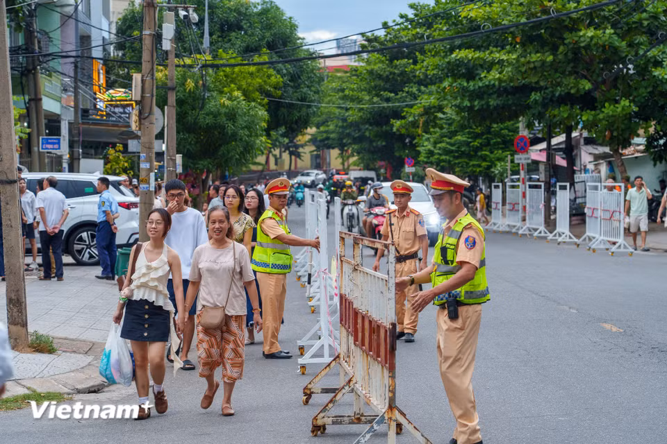 Các chiến sĩ Cảnh sát giao thông căng mình lập rào chắn, phân luồng người đi bộ và các phương tiện để tránh ùn tắc cục bộ. (Ảnh: Thanh Phong/Vietnam+)