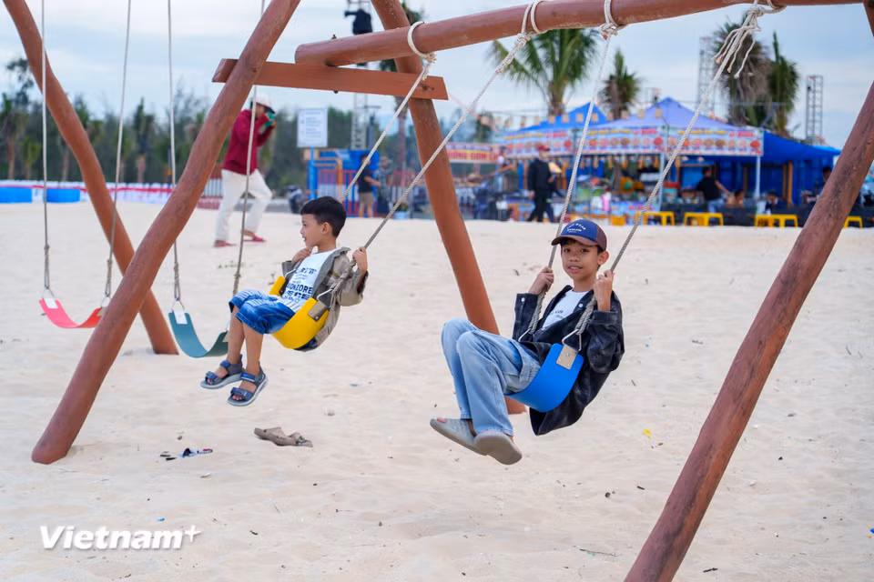 Các em nhỏ thích thú vui chơi trên những chiếc xích đu gỗ được bố trí ngay trên bãi cát trắng mịn của biển Hạ Thanh. (Ảnh: Thanh Phong/Vietnam+)
