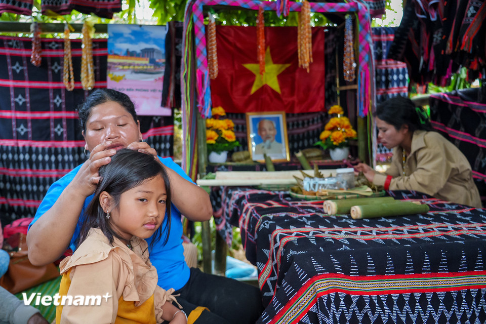 Khoảnh khắc bình yên, ấm áp tình mẫu tử của người mẹ Cơ Tu bên gian hàng trưng bày thổ cẩm truyền thống. (Ảnh: Thanh Phong/Vietnam+)