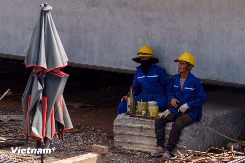 Phút nghỉ ngơi hiếm hoi của các công nhân. Họ tranh thủ ngả lưng, tránh nắng ngay dưới bóng râm của những bệ mố trụ cầu vừa hoàn thành. (Ảnh: Thanh Phong/Vietnam+)