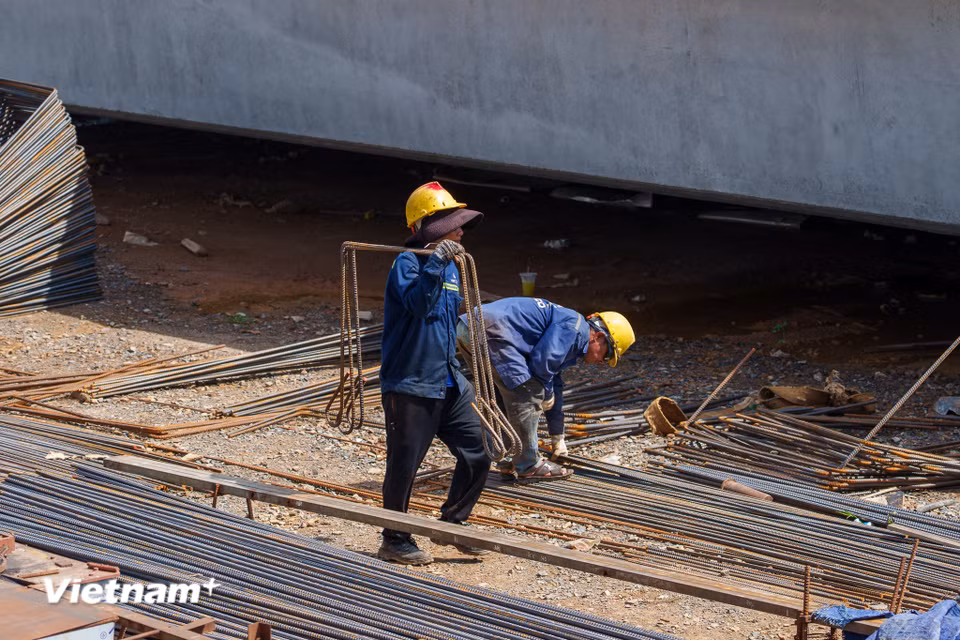 Thời tiết khắc nghiệt khiến công việc vác những bó thép nặng trĩu trên vai của người thợ càng trở nên vất vả, tốn rất nhiều sức lực. (Ảnh: Thanh Phong/Vietnam+)