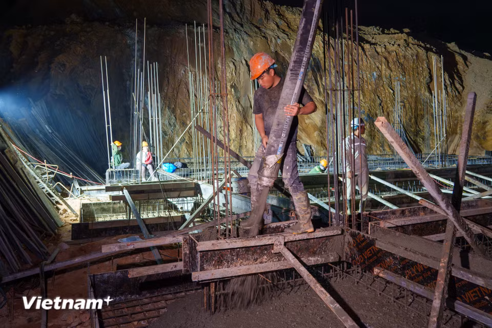Nam công nhân dồn toàn lực ôm chặt ống bơm cao su, điều hướng dòng bê tông đặc quánh chảy đều vào các ván khuôn đã được ghép sẵn. (Ảnh: Thanh Phong/Vietnam+)