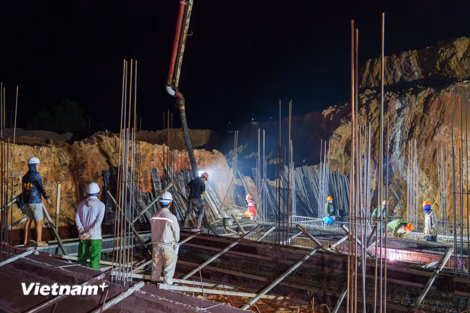 Tại khu vực hố móng, hàng chục công nhân bám sát vị trí, chờ đợi dòng bê tông tươi đổ xuống để nhanh chóng san gạt, đầm dùi. (Ảnh: Thanh Phong/Vietnam+)