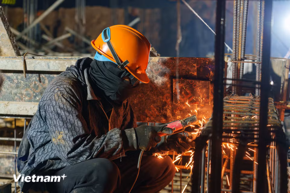 Ở một phân khu khác, những người thợ đang miệt mài gia cố hệ thống khung thép dầm sàn. Ánh lửa hàn rực sáng xé toạc màn đêm tĩnh mịch. (Ảnh: Thanh Phong/Vietnam+)