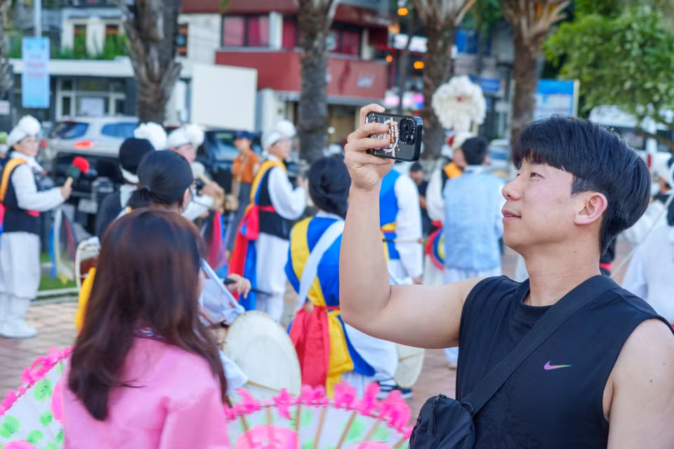 Vẻ đẹp đa sắc màu của buổi diễu hành khiến nhiều du khách và người dân thích thú dùng điện thoại ghi lại. (Ảnh: Thanh Phong/Vietnam+)