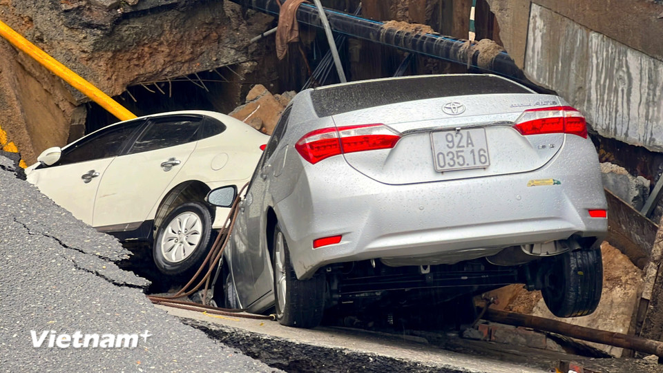 Theo ghi nhận của phóng viên, ở thời điểm tiếp cận hiện trường phố Nguyễn Công Trứ, có hai ô tô con đang đỗ sát lề đường bị rơi xuống hố, một ôtô con khác nằm vắt vẻo trên miệng hố. (Ảnh: Thanh Phong/Vietnam+)