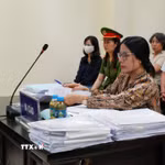 Bị cáo Nguyễn Thị Bình (đeo kính) và bị cáo Phạm Thị Minh Nguyệt (mặc áo sẫm màu, đeo khẩu trang trắng) tại phiên xử. (Ảnh: Kim Anh/TTXVN)