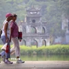 Du khách nước ngoài đi dạo bên hồ Hoàn Kiếm. (Ảnh: Tuấn Đức/TTXVN)