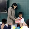 Cô giáo chủ nhiệm trao quà cho em Nguyễn Anh Tín, học sinh lớp 5D Trường tiểu học Lâm Hưng, bị thiệt hại nặng do mưa lũ. (Ảnh: Hồng Hiếu/TTXVN)