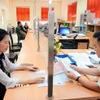 Hướng dẫn người dân làm thủ tục nộp thuế trước bạ. (Ảnh: Phạm Hậu/TTXVN)